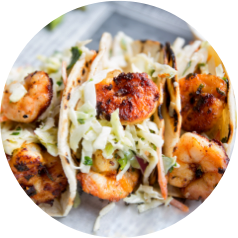 Grilled shrimp tacos with coleslaw in soft tortillas on a plate, ready to be served.