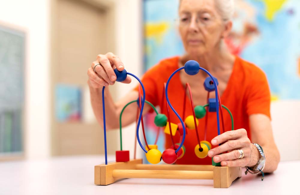 Senior woman engaging in a cognitive activity with a bead maze toy to enhance memory skills.